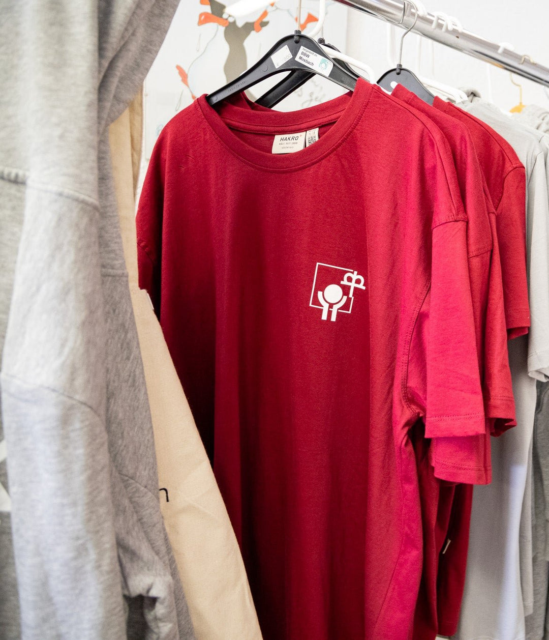 Zwei rote T-Shirts mit dem Johannes-Diakonie Logo, Hängend auf einer Kleiderstange