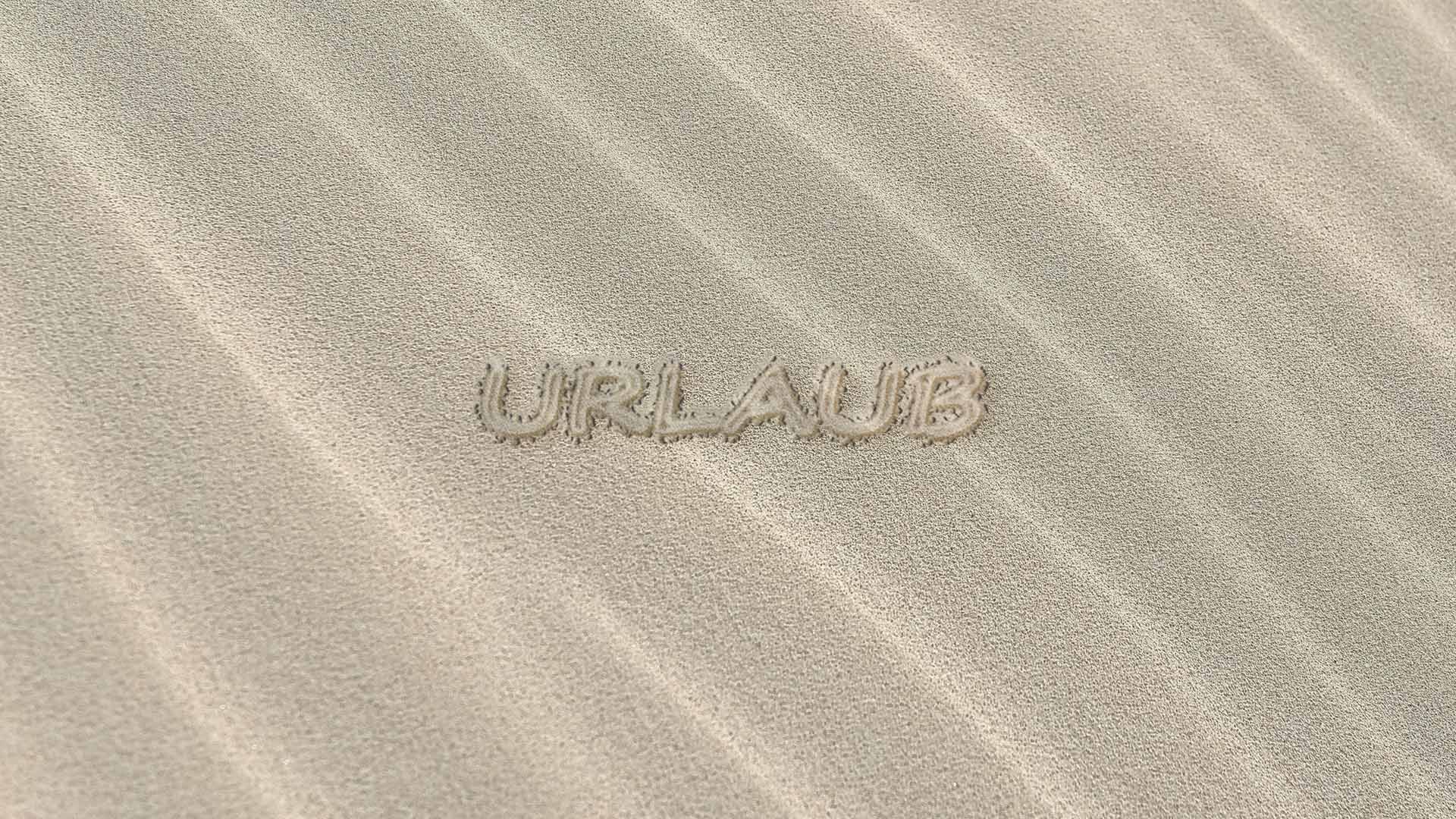 Sandstrand auf dem das Wort "Urlaub" eingeschrieben wurde 